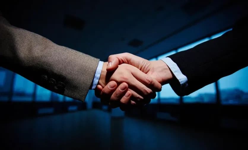 Two people in business suits shaking hands