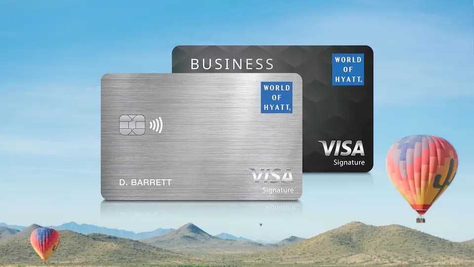 The two World of Hyatt Visa credit cards, personal and business, above a desert landscape with hot air balloons