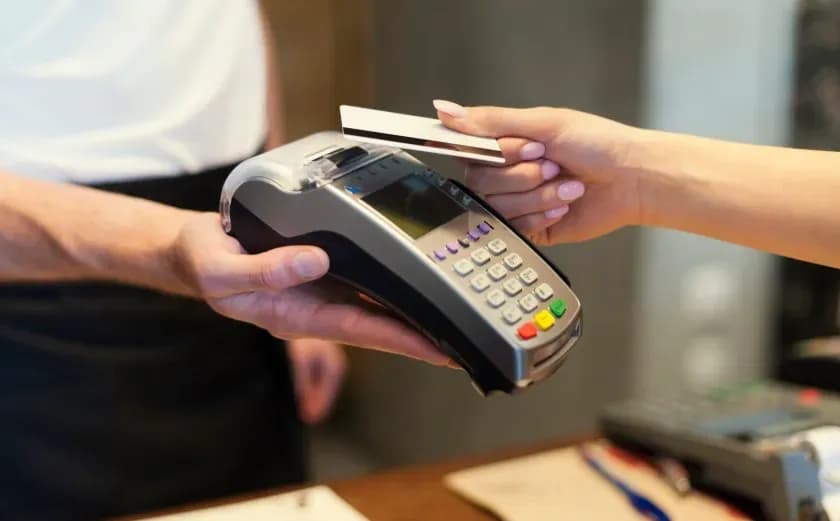 Customer tapping a card on a handheld payment terminal held by a shop assistant