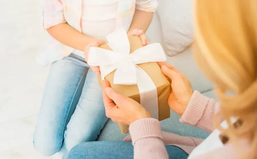 One person handing a gift box tied with a white ribbon to another