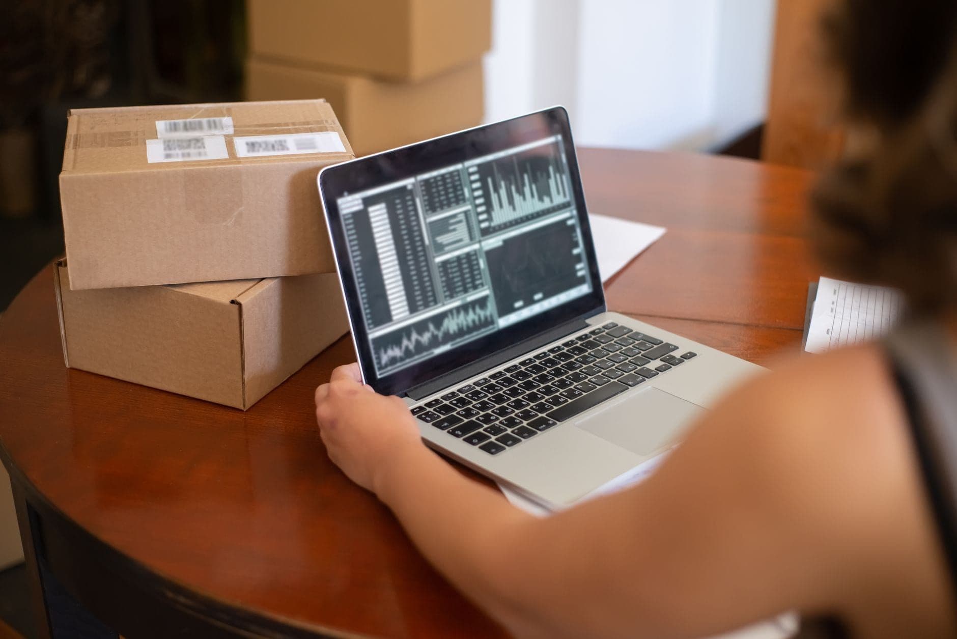 Small business owner managing online orders on a laptop surrounded by parcels