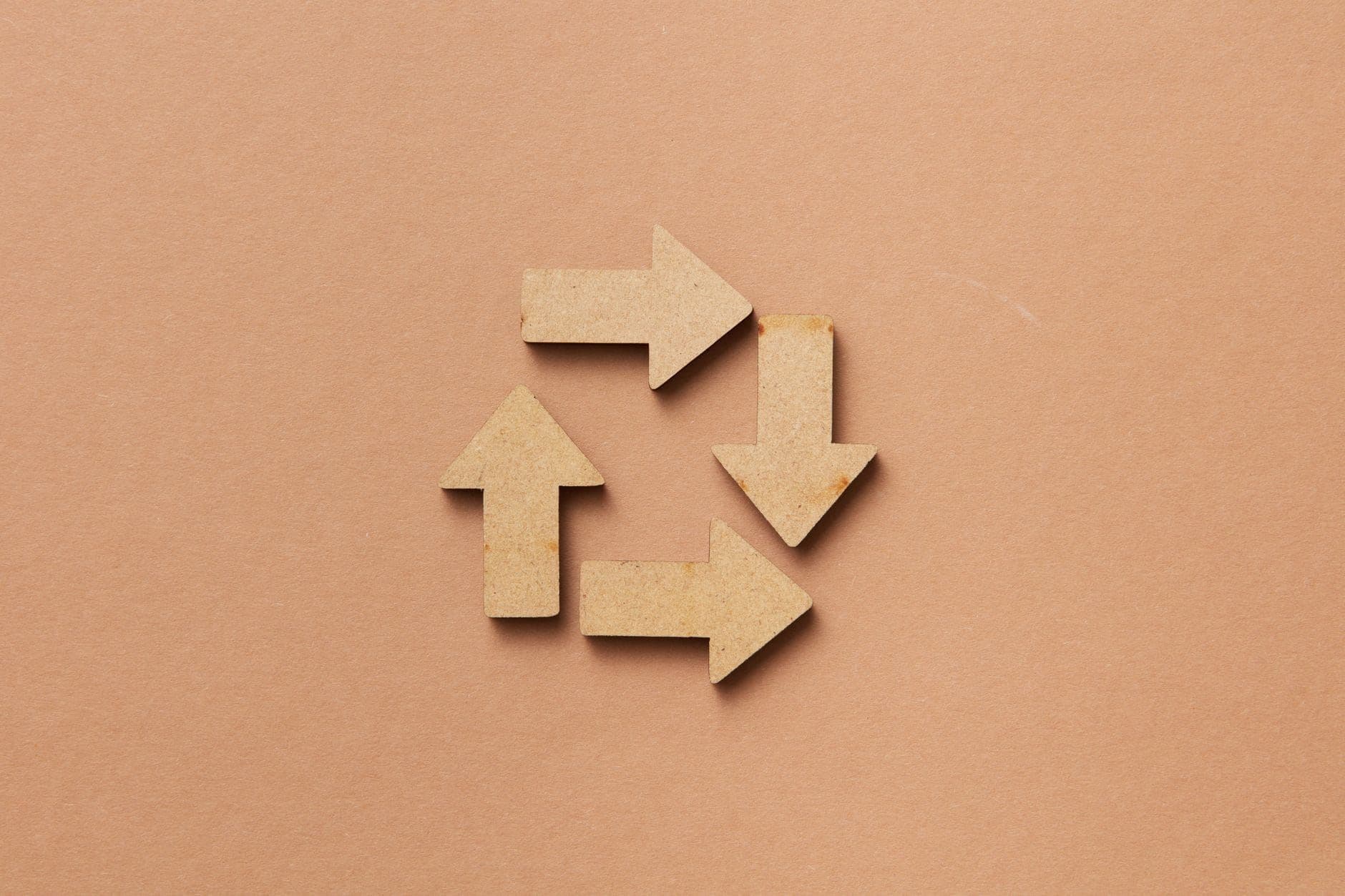 Wooden arrows arranged into a closed loop on a beige background