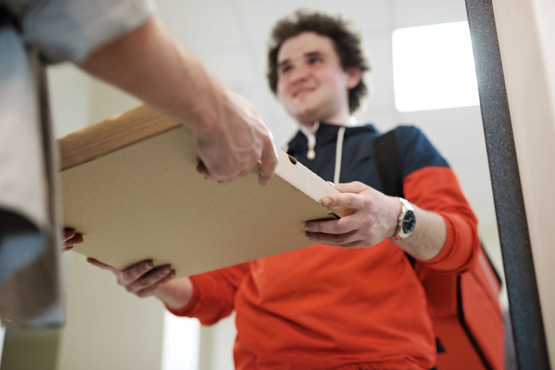 Delivery person handing a pizza box to a smiling customer