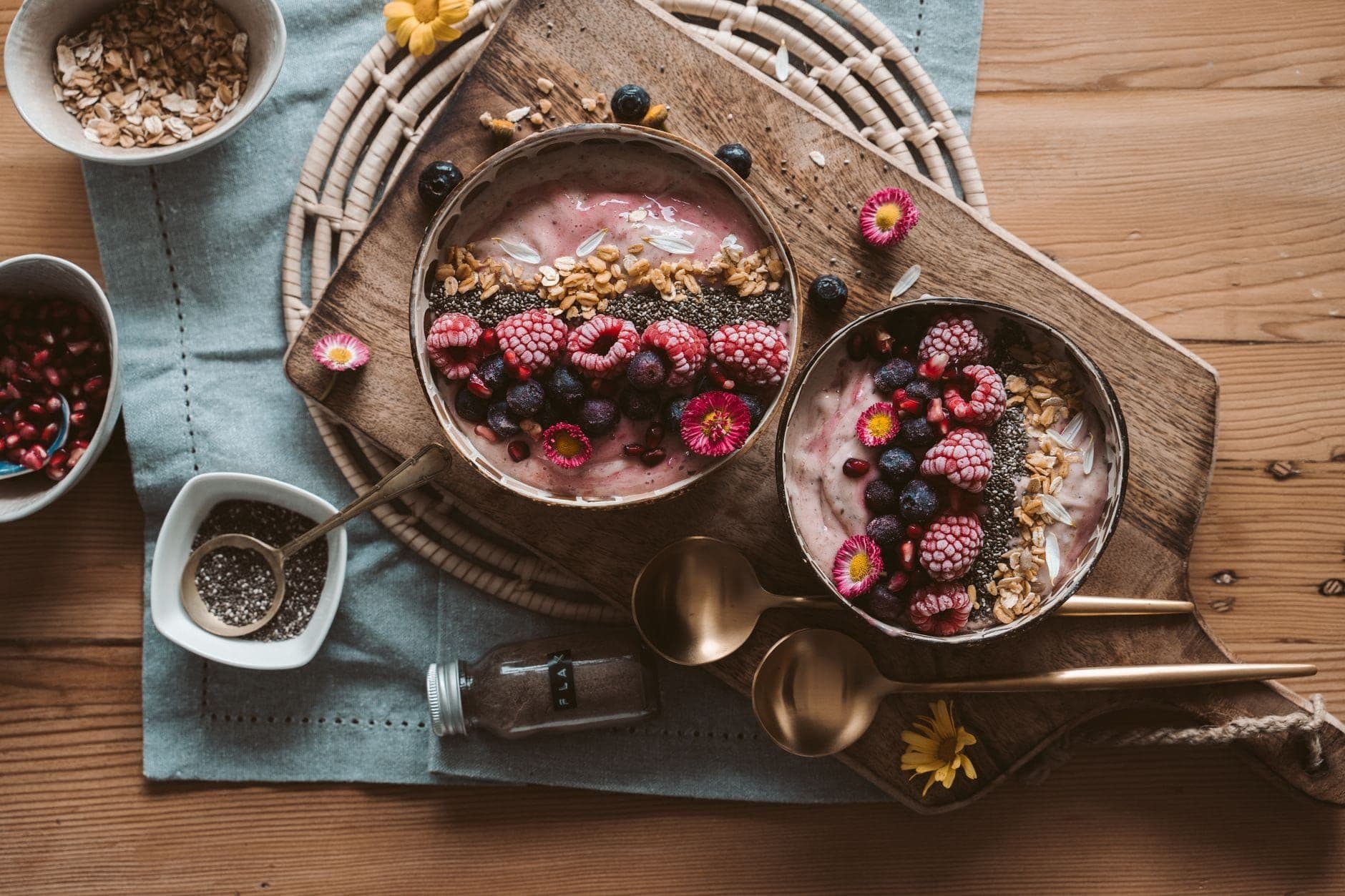 Smoothie bowls with granola and berries on a rustic wooden board