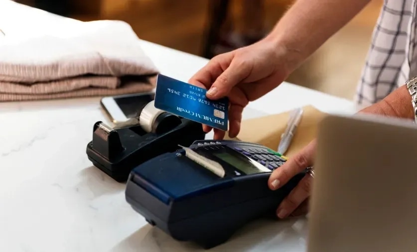 Customer paying by card at a shop counter, the moment a store-credit reward would be earned