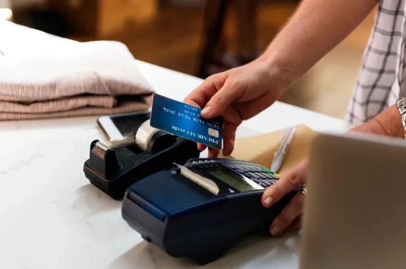 Customer tapping a credit card on a card reader at a store counter