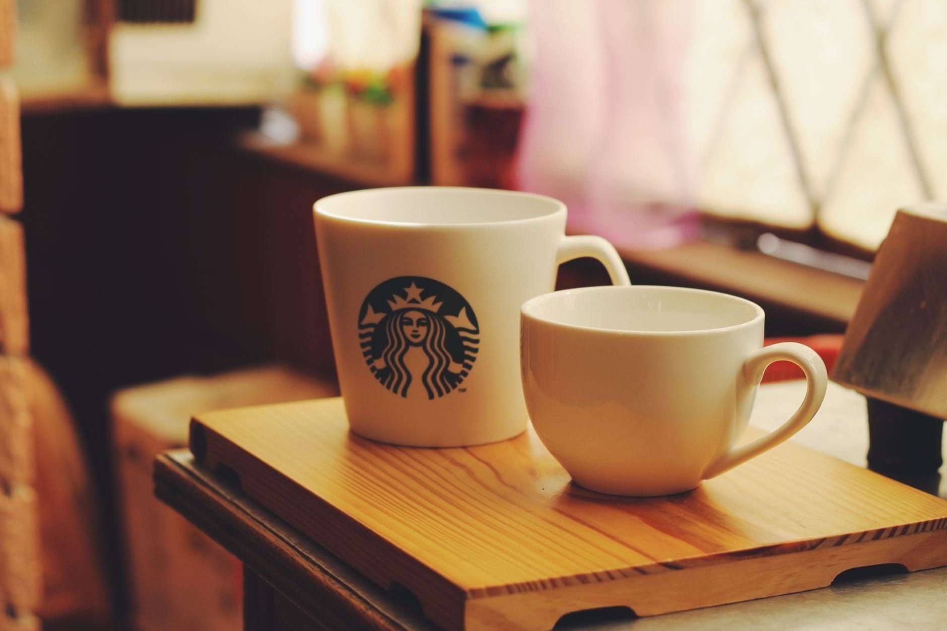 Two Starbucks ceramic cups on a wooden tray