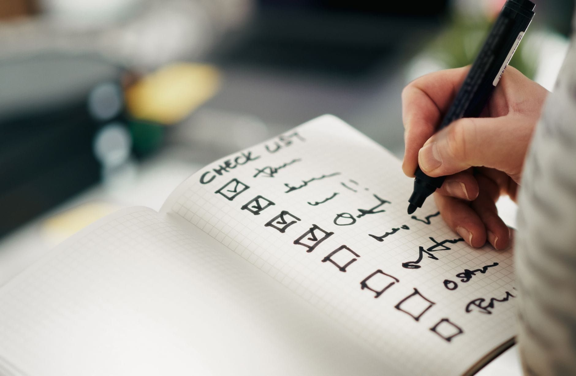 Hand writing a checklist with tick boxes in a notebook