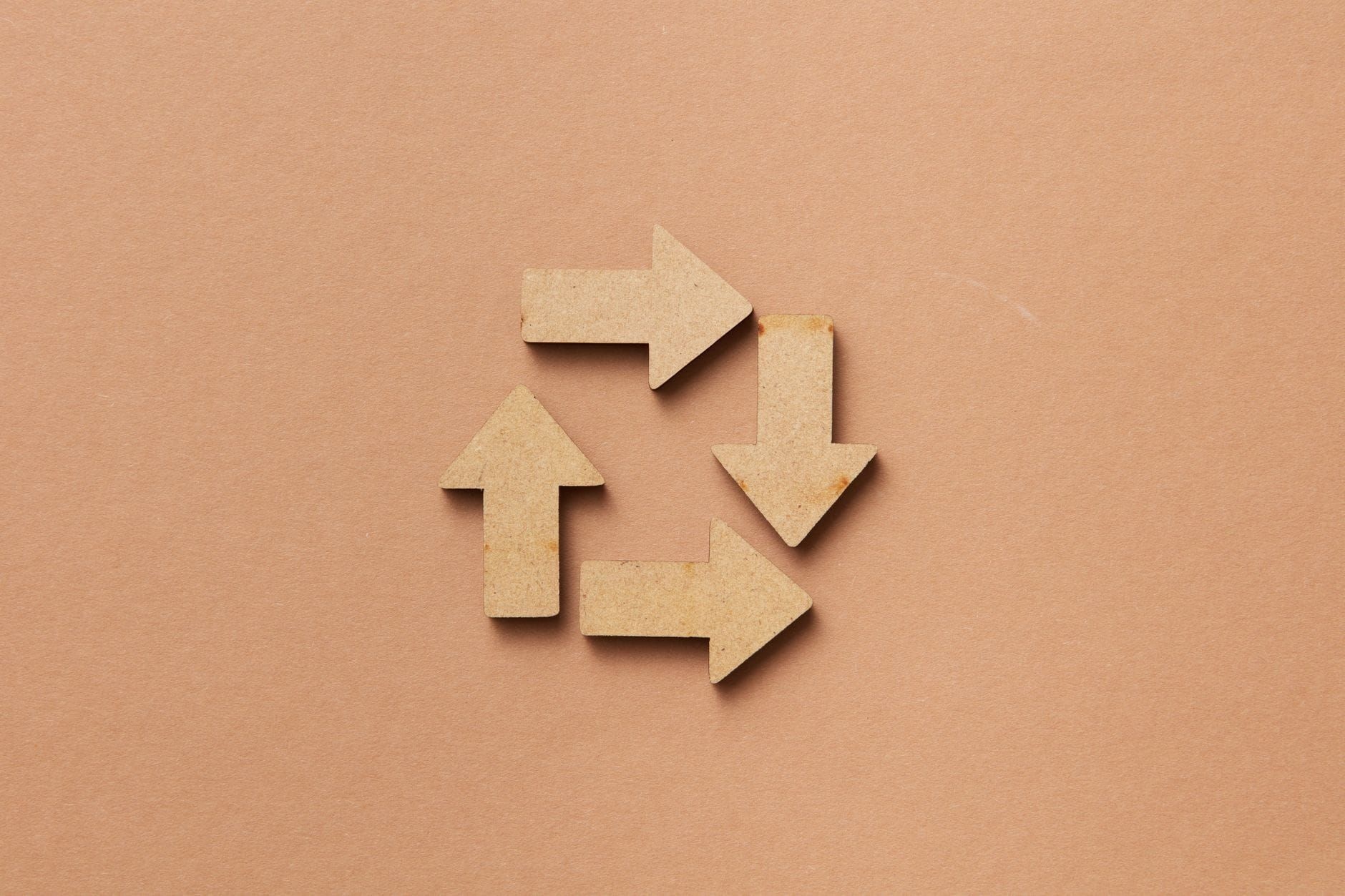 Wooden arrows arranged into a closed loop on a beige background