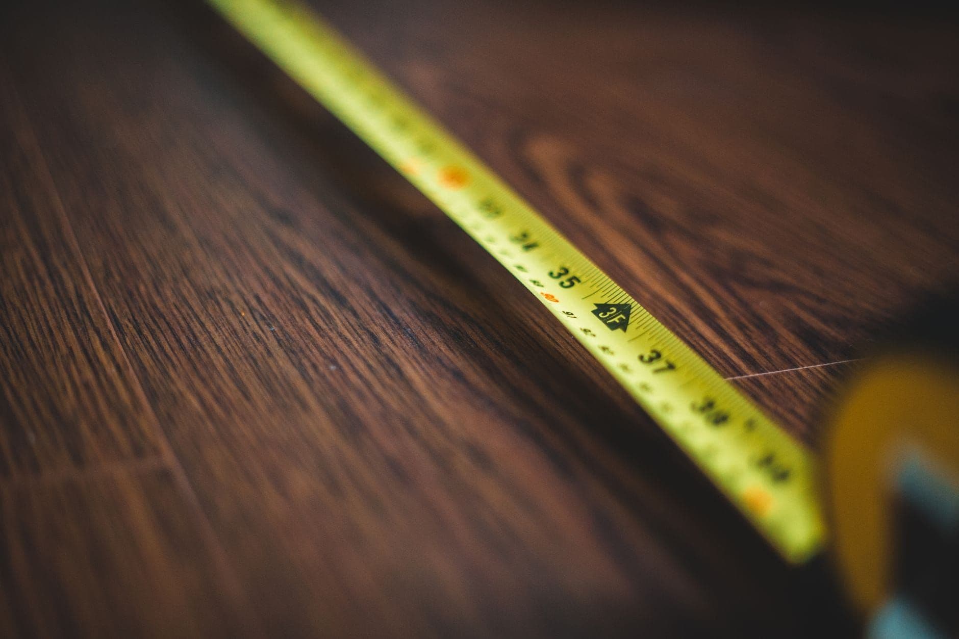 Yellow tape measure extended across a dark wooden floor