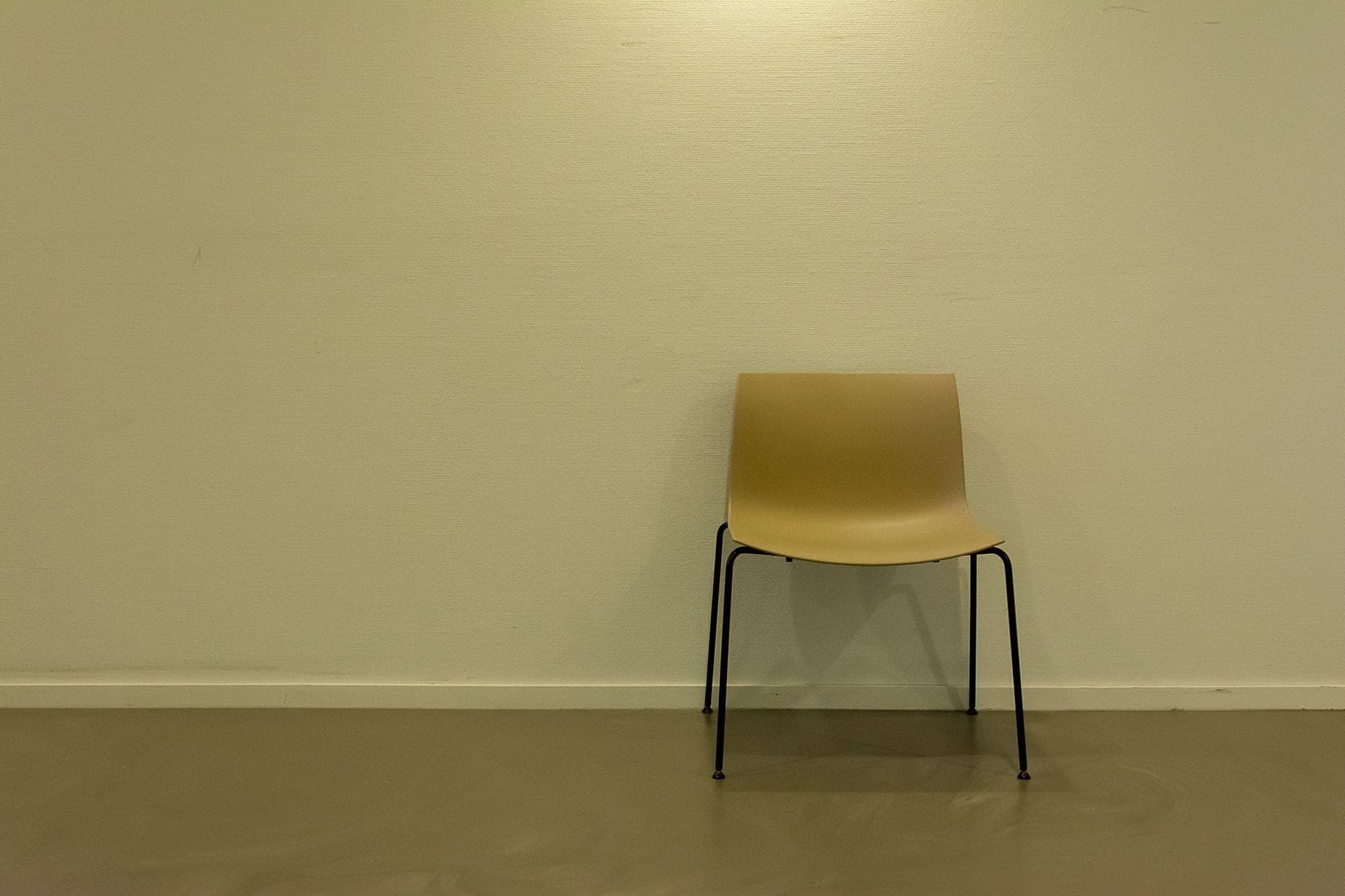 A single empty chair standing against a plain wall