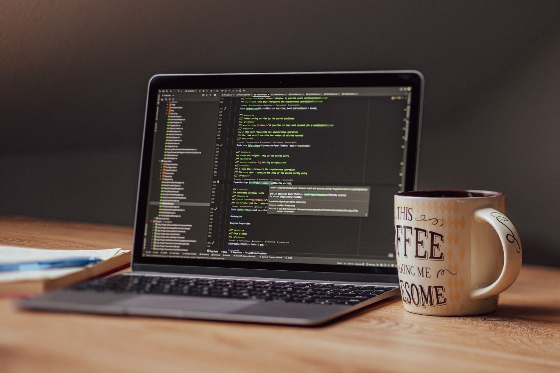 Laptop showing a code editor beside a coffee mug on a desk
