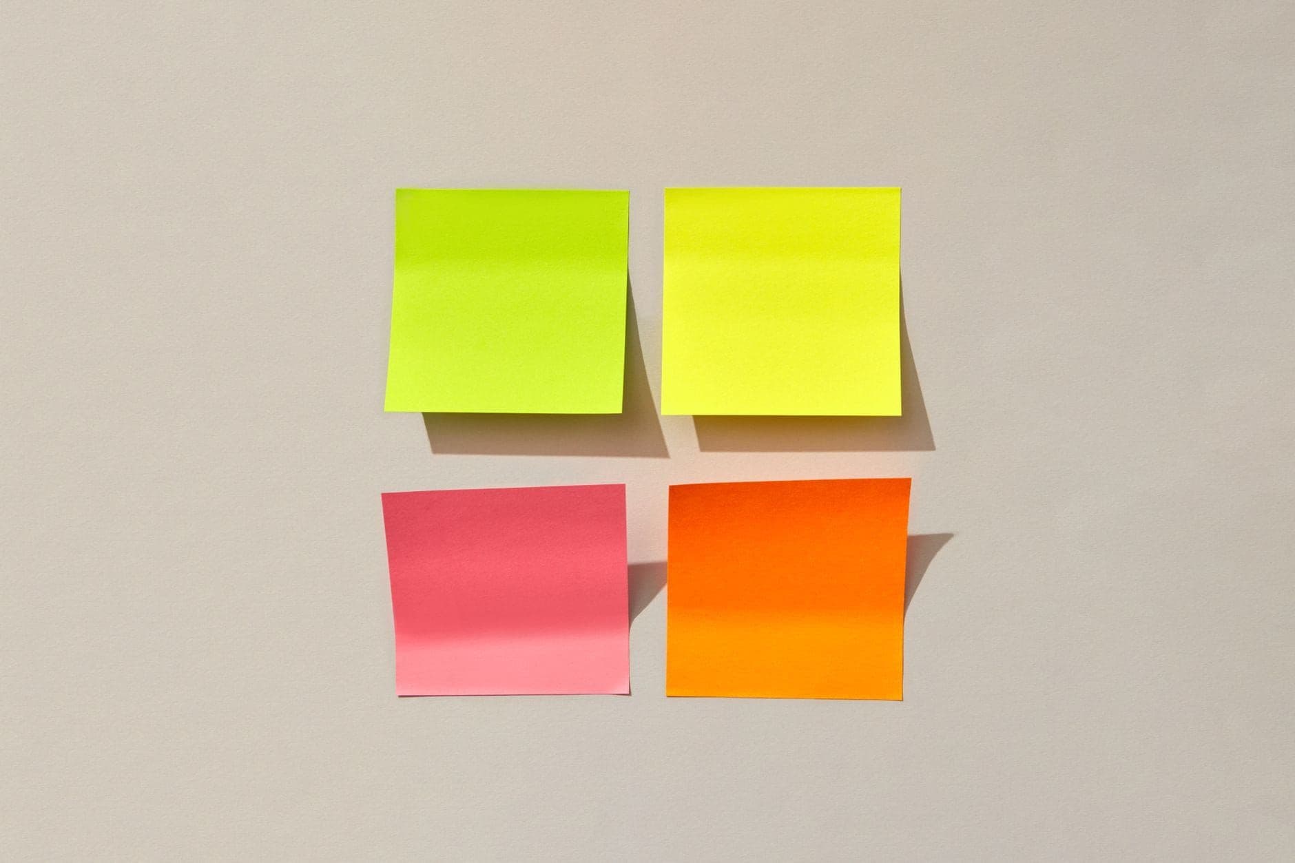 Four coloured sticky notes arranged in a square on a neutral wall
